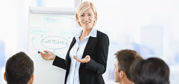 A woman standing in front of a whiteboard giving a presentation